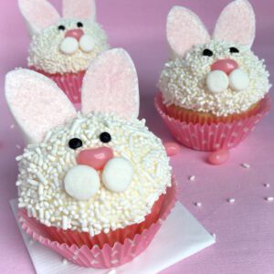 cupcakes with icing that looks like a bunny face with marshmallow ears and a jelly bean nose.