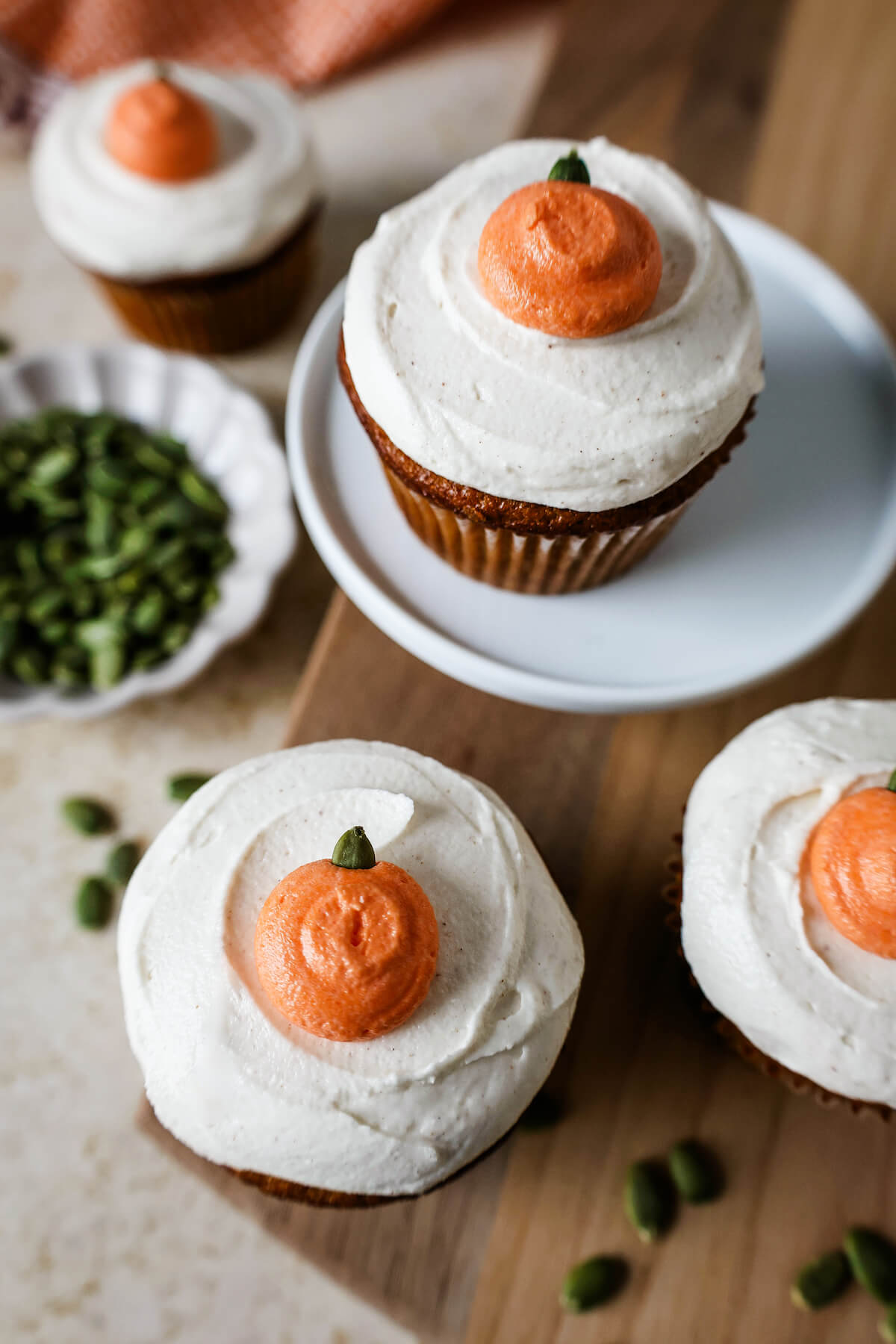 Pumpkin spice cupcakes with frosting and an orange frosting pumpkin on top as garnish.