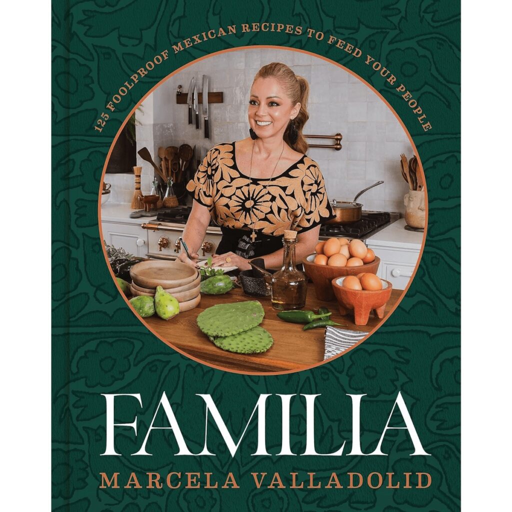 Cover of the book Familia by Marcela Valladolid, which is a forest green flower print and has an image of the author in her kitchen on the cover.