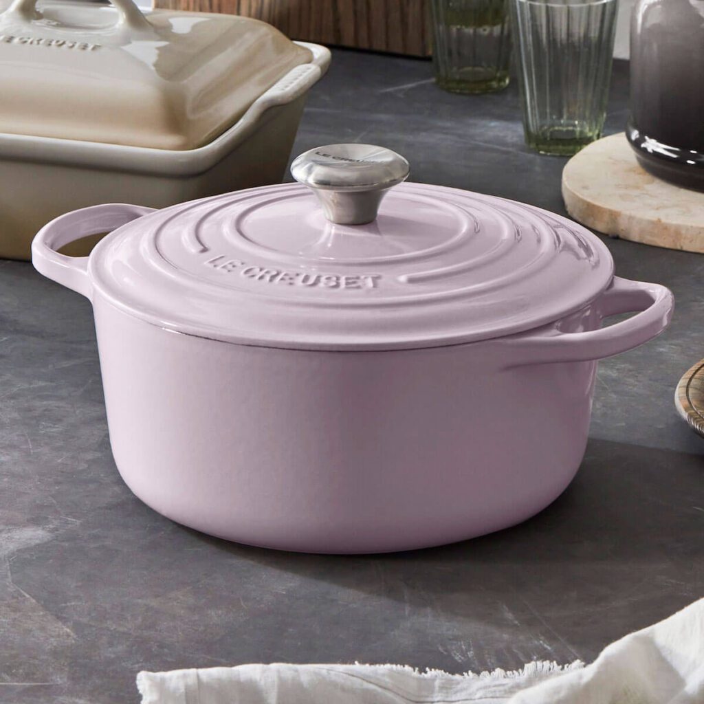 Le Creuset Enameled Cast iron Signature Oval Dutch Oven with lid in size 6.75 in the color shallot, set in a kitchen with a slate table top and surrounded by other le Creuset Pots.