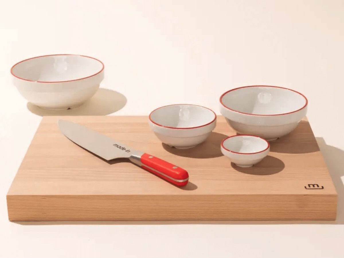 One of Each red Made in Mise en Place bowl size set on a wood cutting board alongside a red-handled knife.