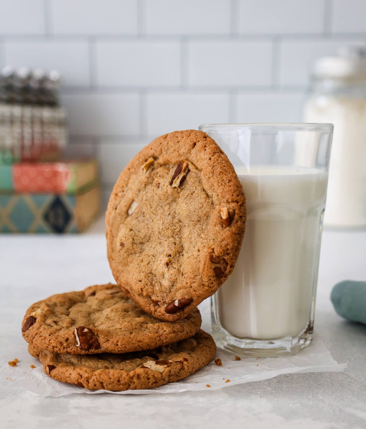 A stack of crispy pecan cookies with a glass of milk.