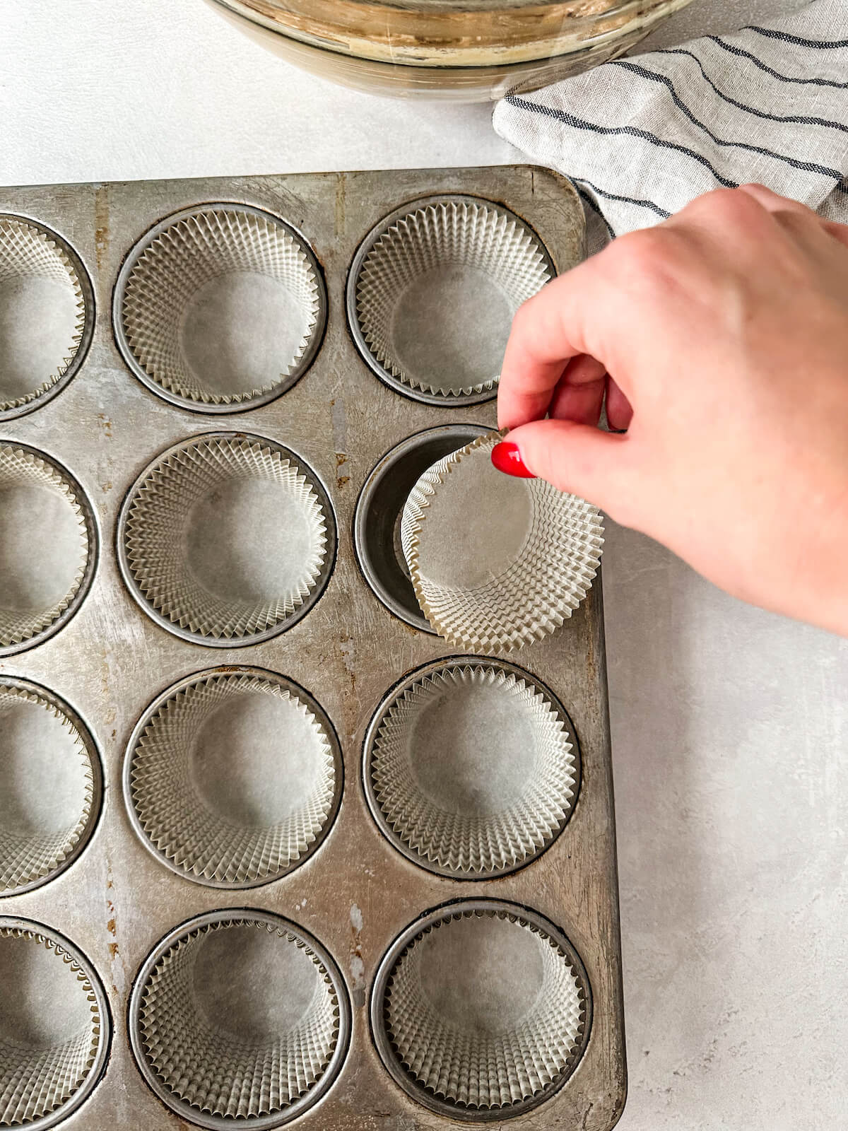 Adding muffin papers to a muffin tin.