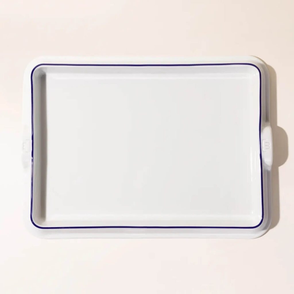 An image of the white Made-In baking slab with a royal blue rim, set over a light pink plain background.