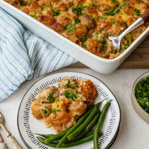 A spoonful of meatball tater tot casserole on a plate with a side of green beans.