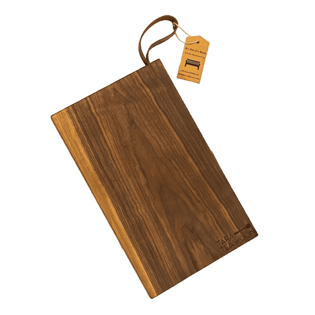 Image of Tara Teaspoon's hand-made wood cutting board with a leather strap.