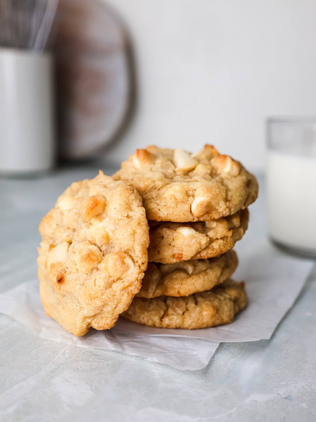 stack of white chocolate macadamia nut cookies with a glass of milk.