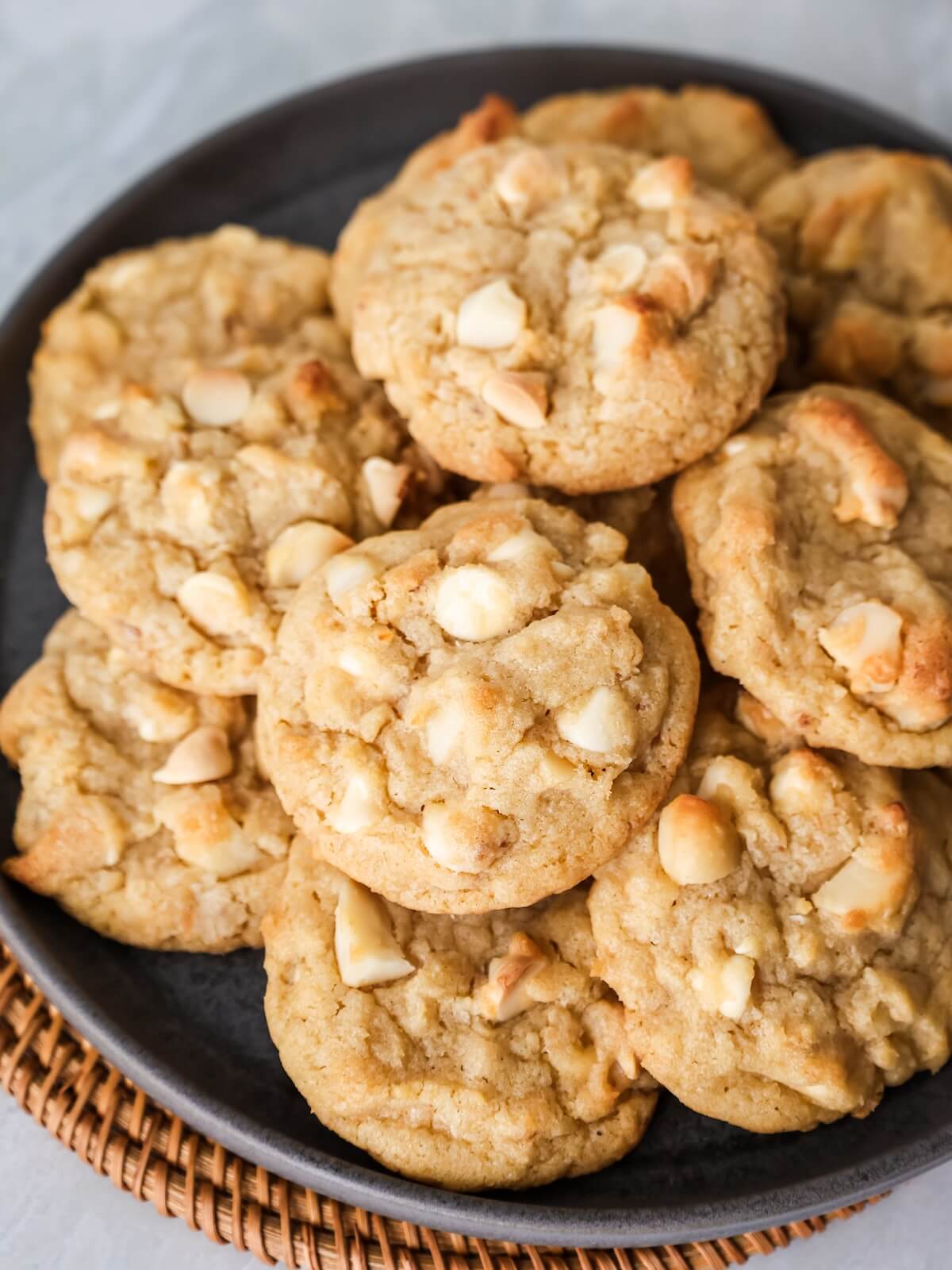 macadamia nut cookies with white chocolate stacked on a plate in a close up image.
