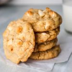 close up stack of macadamia nut cookies on parchment.
