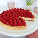 square feature image of raspberry tart cut into so you can see the layers.