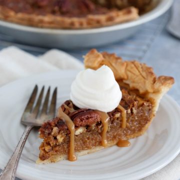 Close up of slice of caramel pecan pie with whipped cream.