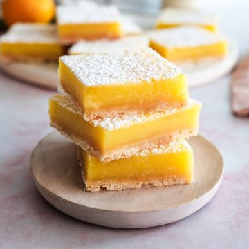 Three cut lemon bars stacked one on top of the other.