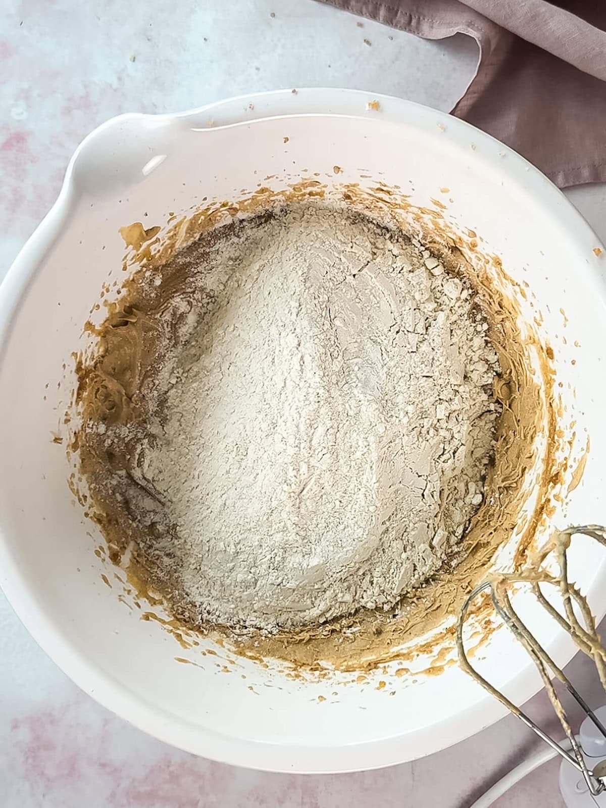 Dry ingredients added to blondie cookie dough in a white mixing bowl.