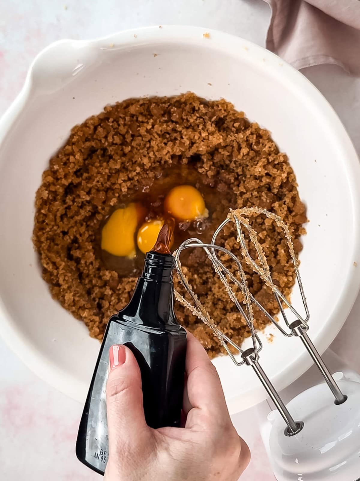 Adding eggs and vanilla to blondie cookie dough in a white mixing bowl.