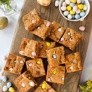 Cut Easter blondies on a cutting board next to a bowl of candy eggs.