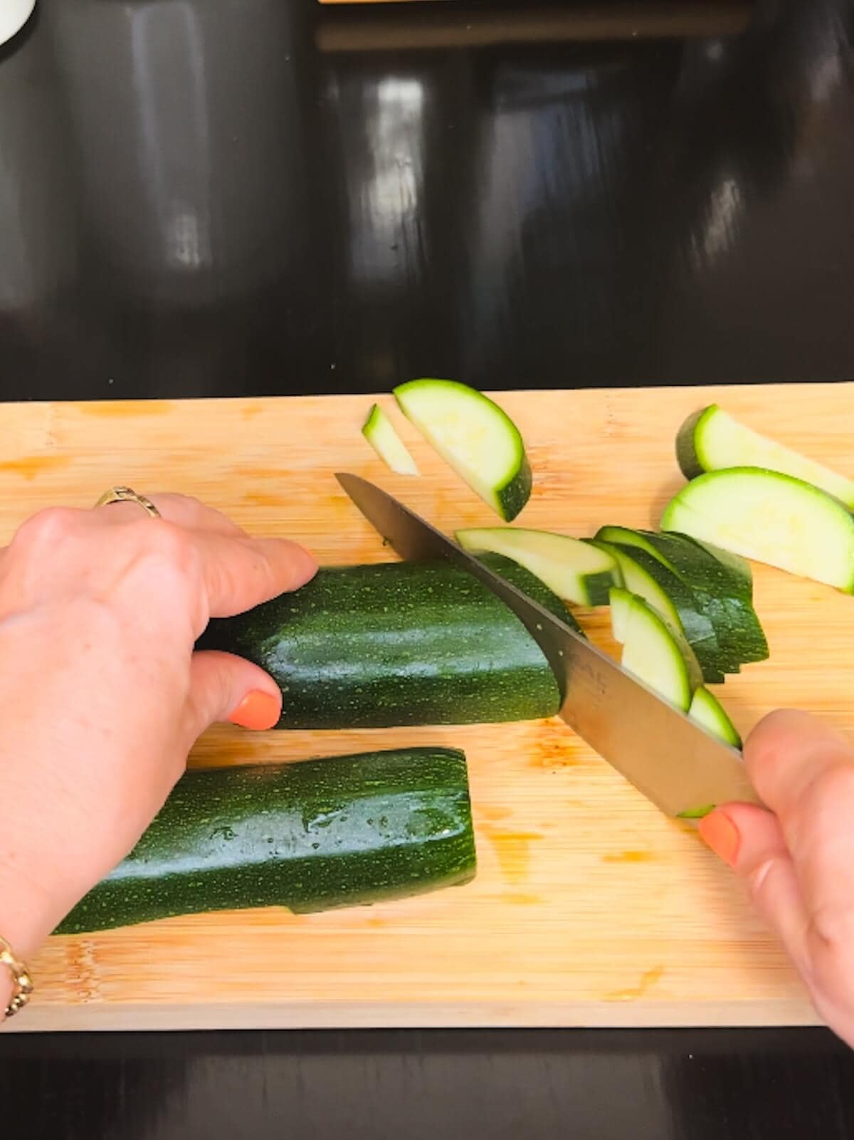 Hand cutting zucchini on a cutting board.