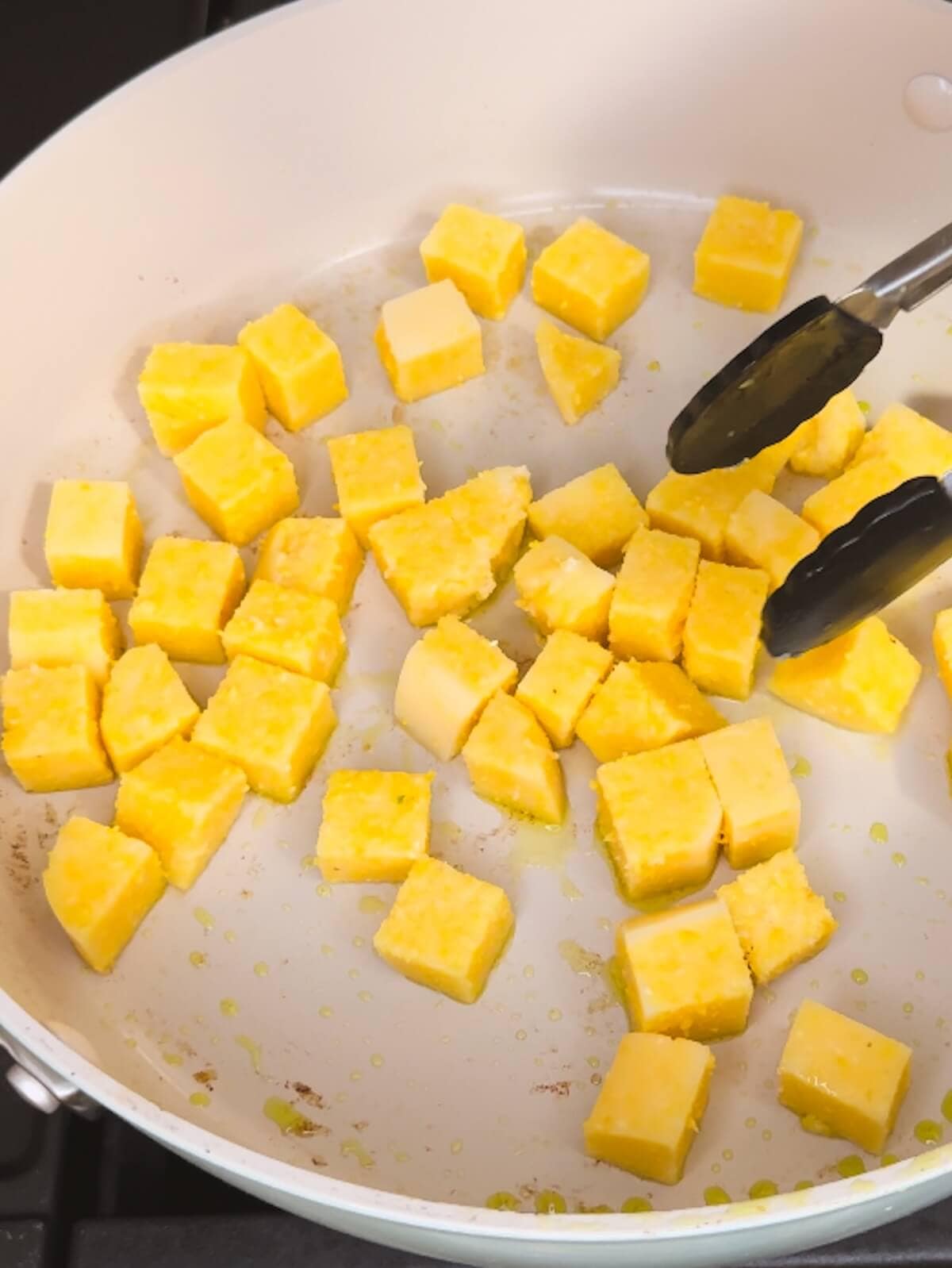 Cubed polenta in a frying pan.