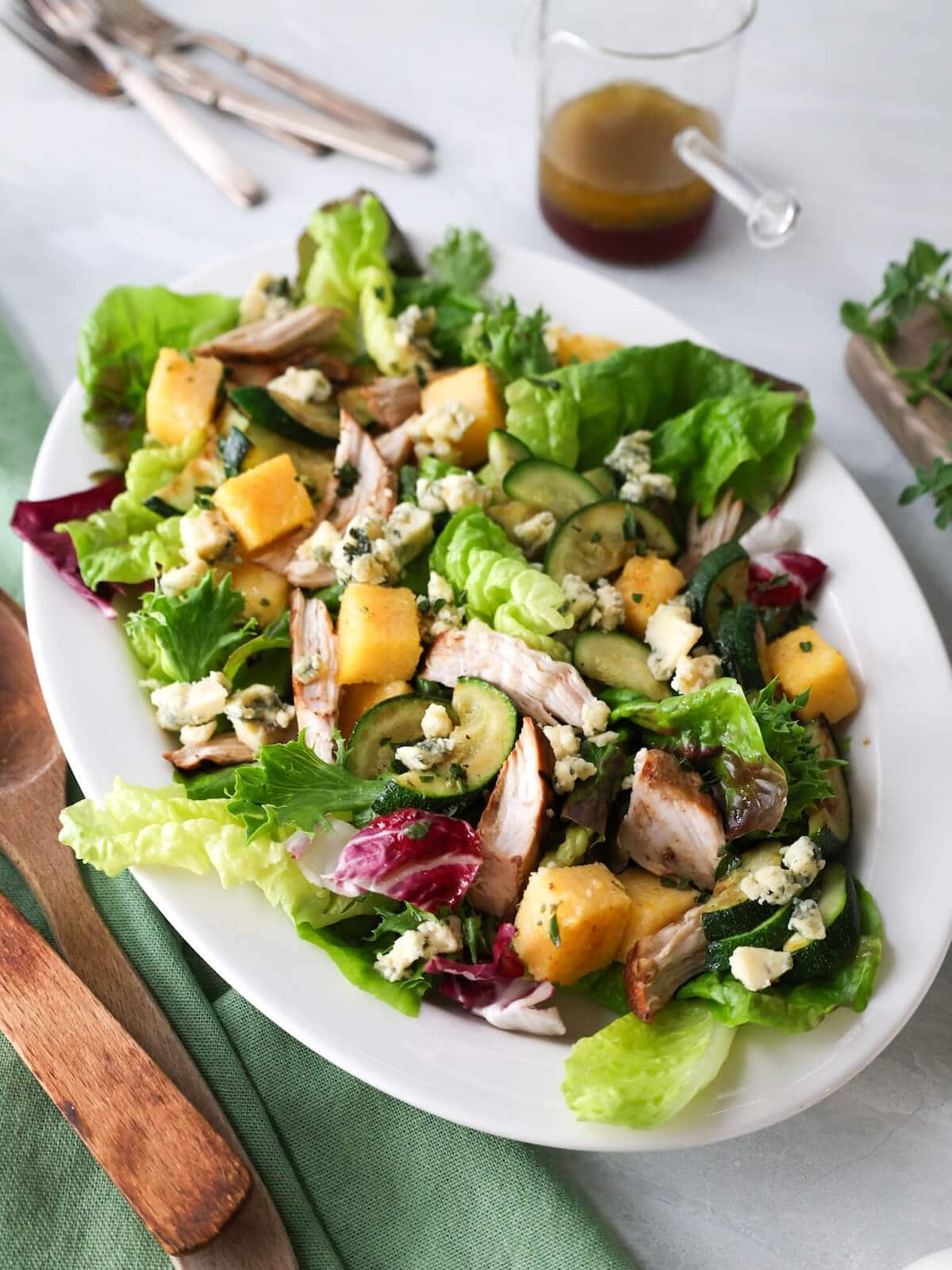 A polenta zucchini salad in a white serving bowl.