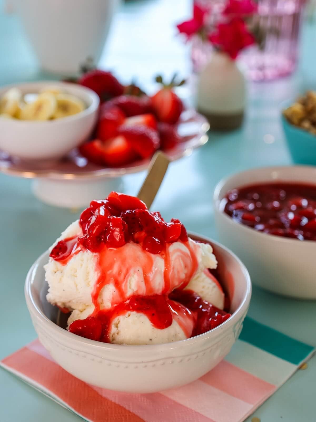 Close up of a bowl of ice cream covered in strawberry sauce.