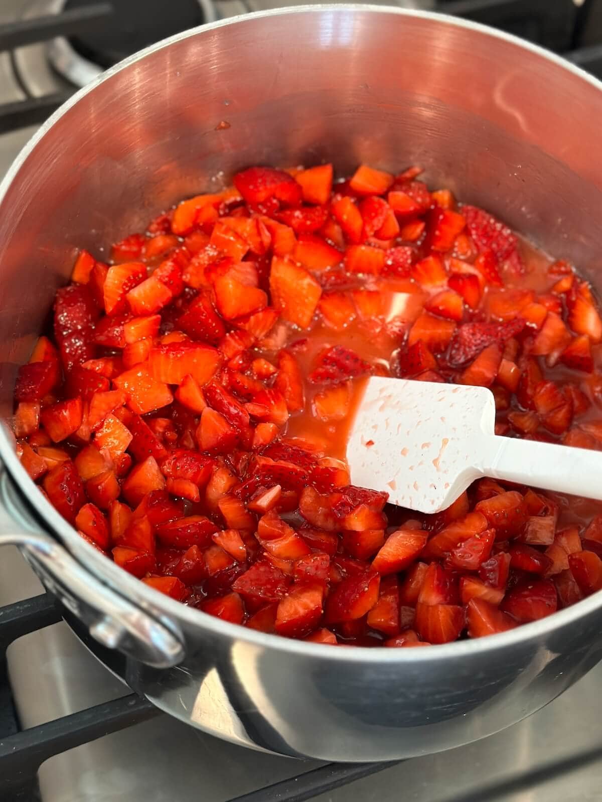 Ingredients for strawberry ice cream sauce in a pot heating on the stove.