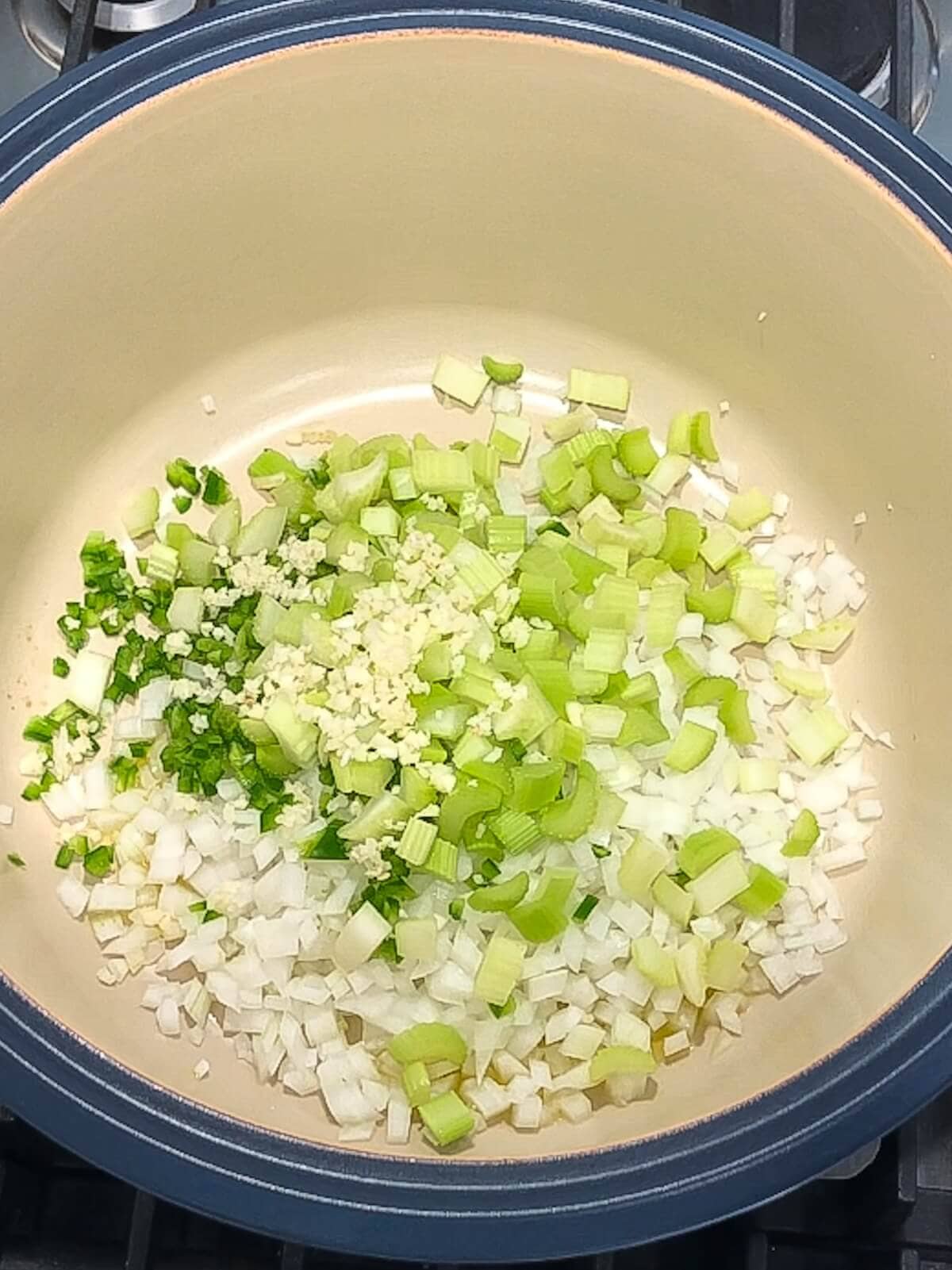 Chopped vegetables and aromatics in the bottom of a pot.