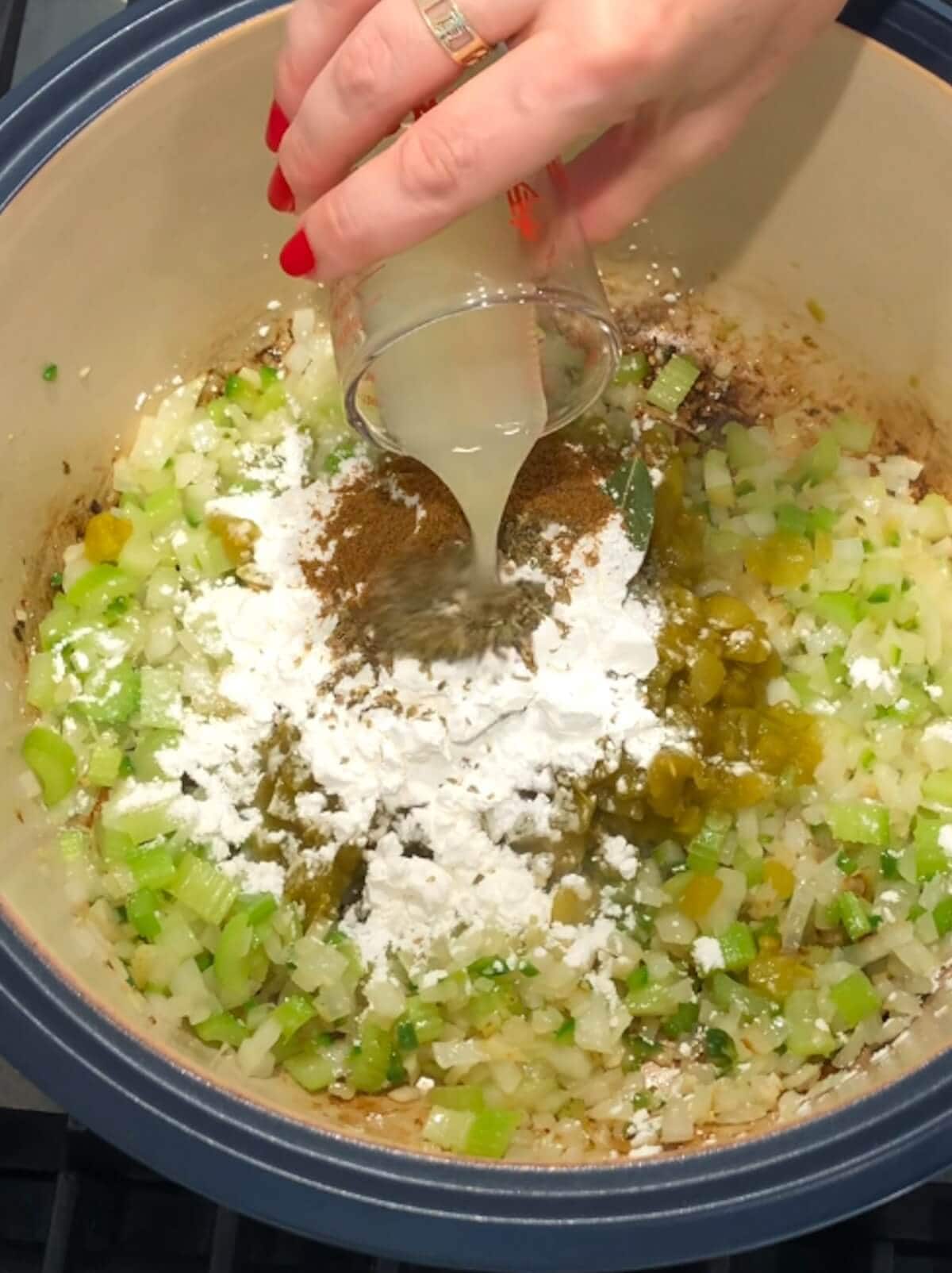 Hand pouring in more spices and lime juice to the base of vegetarian white chili.