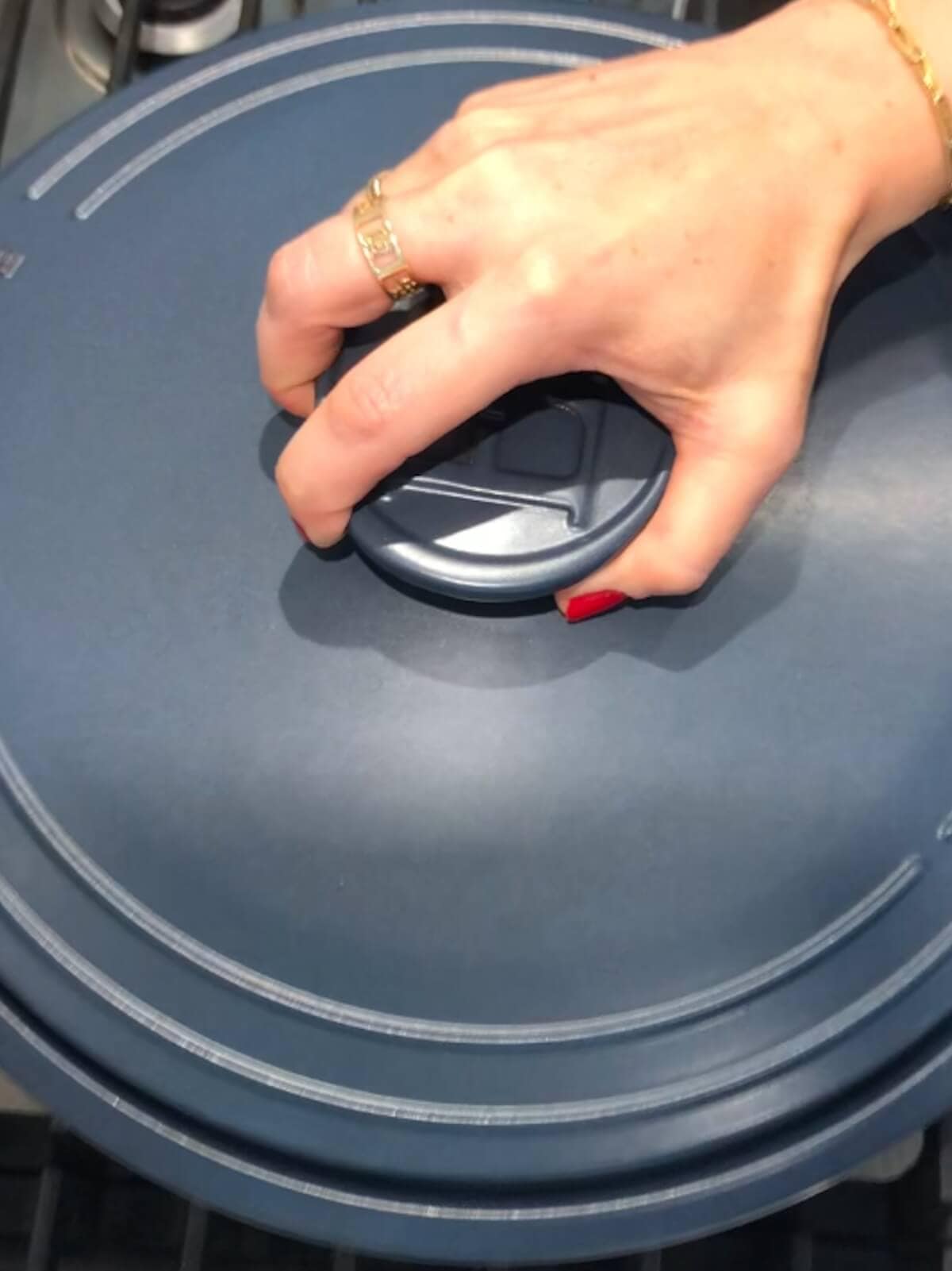 Hand placing a lid on the pot of simmering vegetarian white chili.