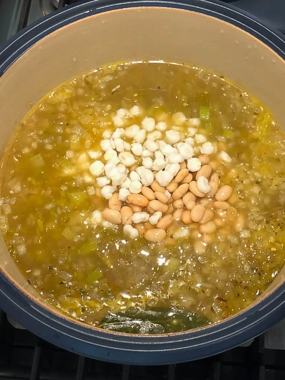 A pot of vegetarian white chili after adding hominy and white beans to the mixture.