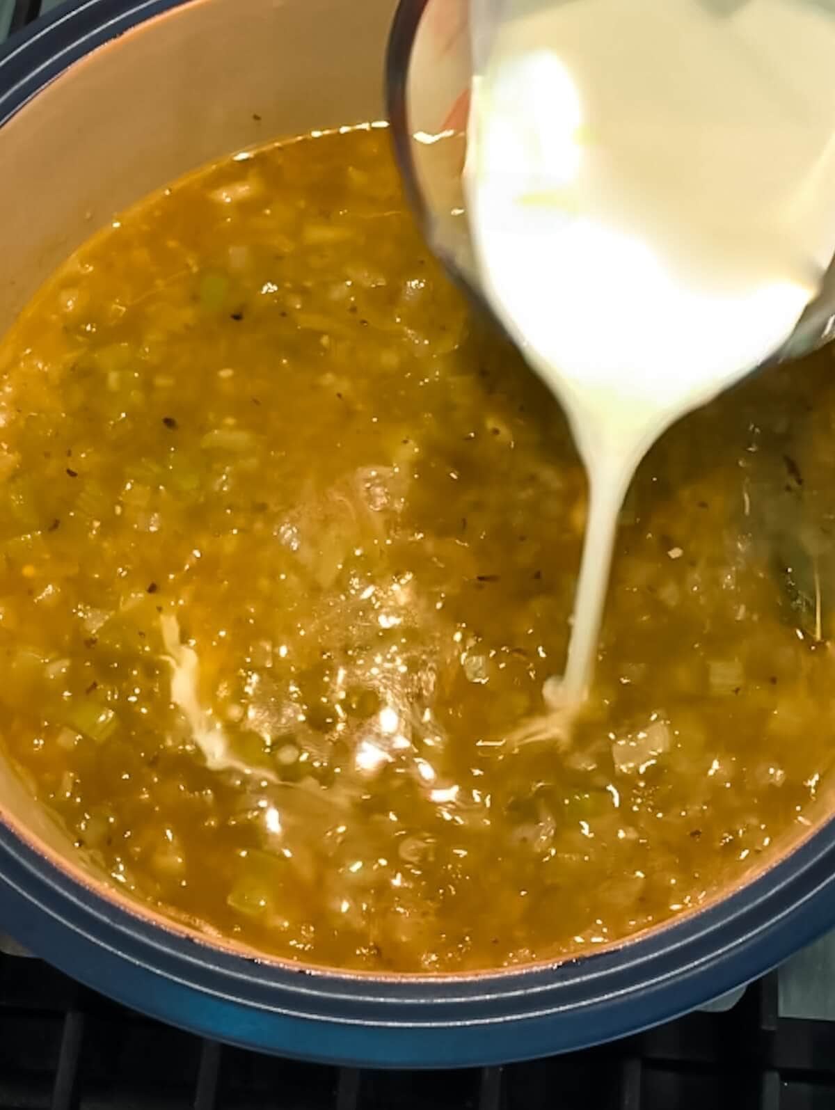 Cream being poured into a pot of vegetarian white chili.
