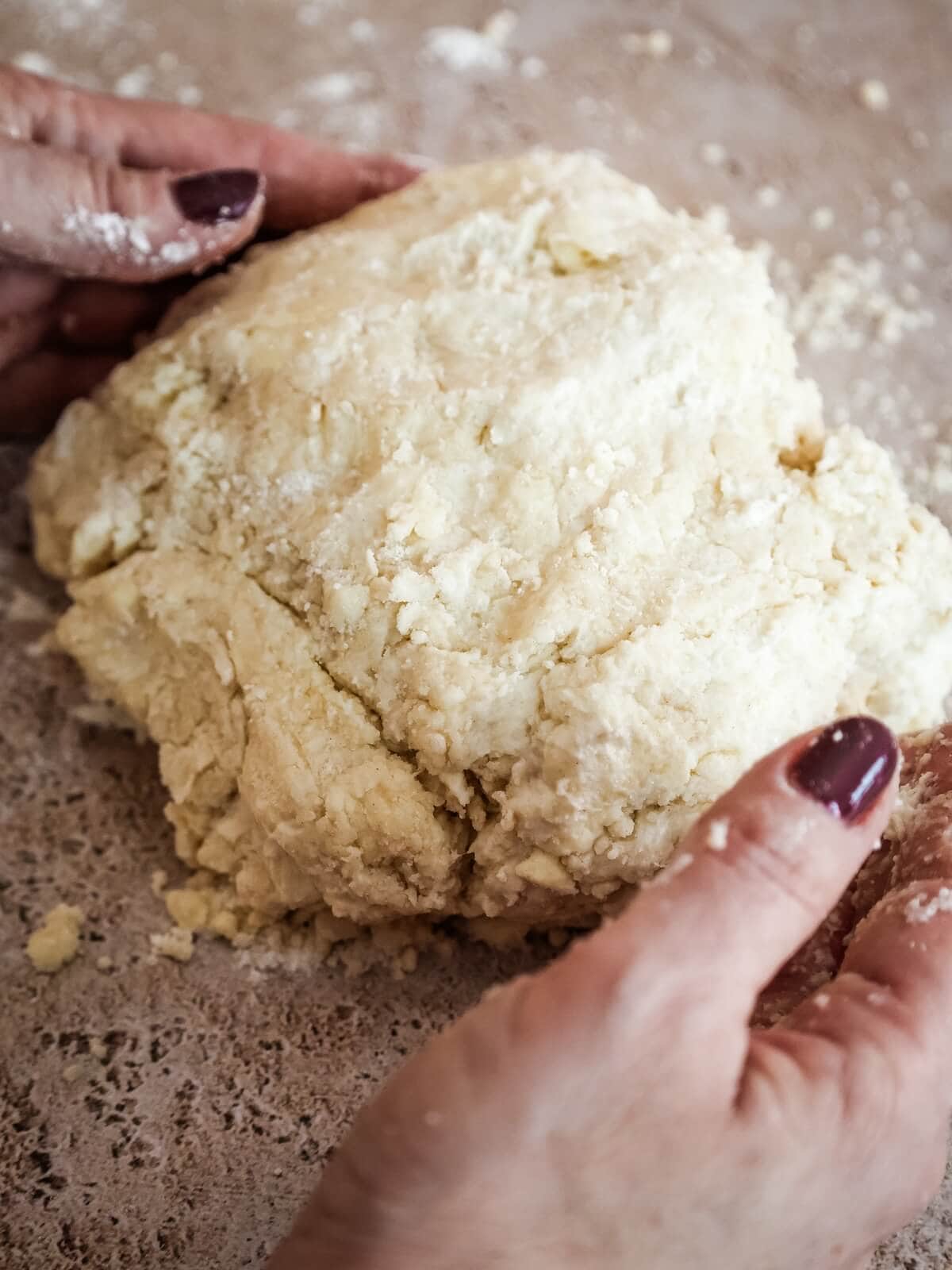 Hands holding crumbly pie crust.