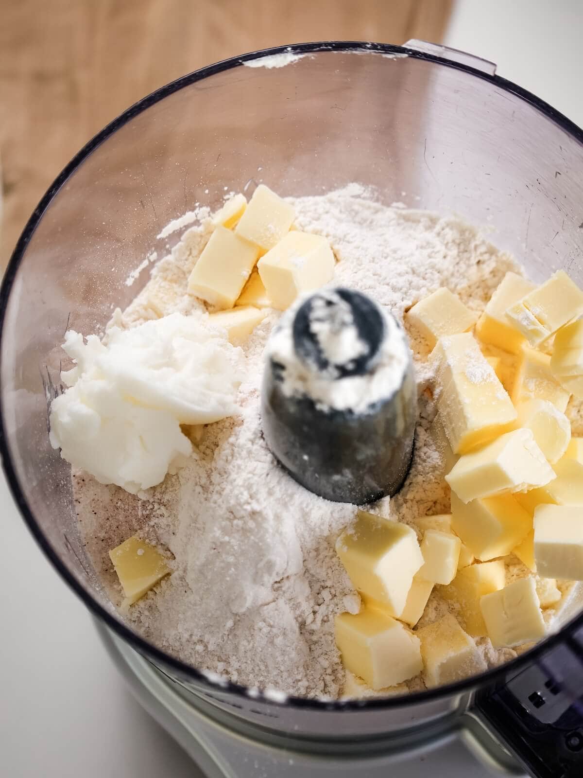 A food processor bowl holding pie crust ingredients.
