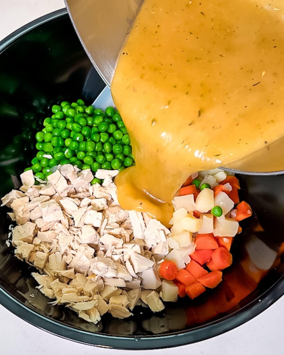 Gravy being poured over pot pie ingredients in an Instant Pot.