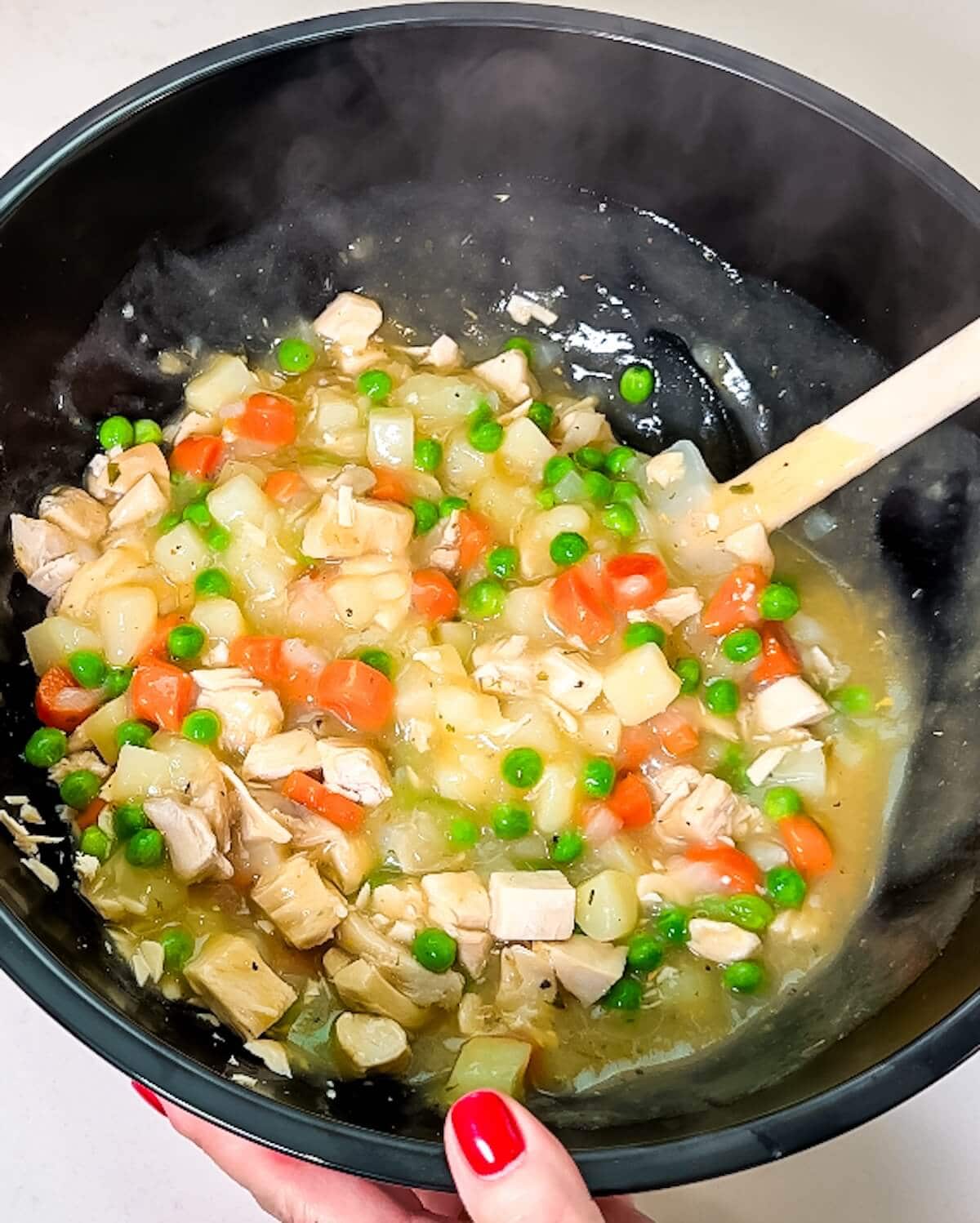 Mixed turkey pie filling being stirred with a spatula.