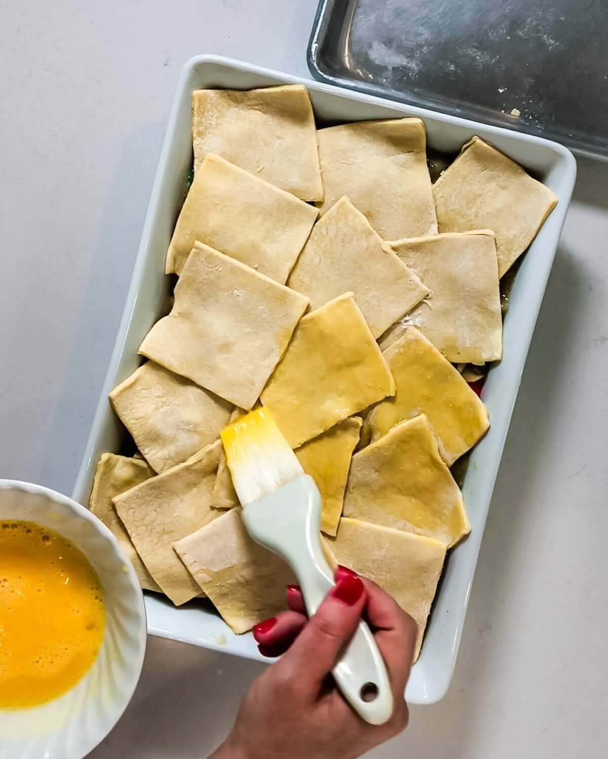 Hand brushing puff pastry with egg.