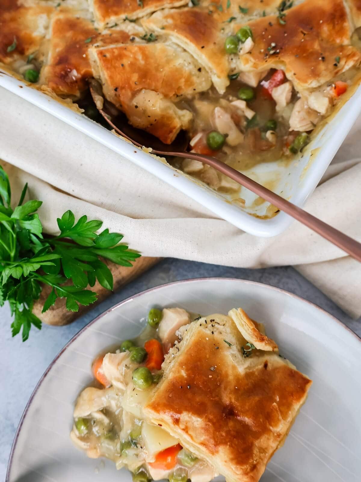 turkey pot pie serving on a plate with a puff pastry crust.