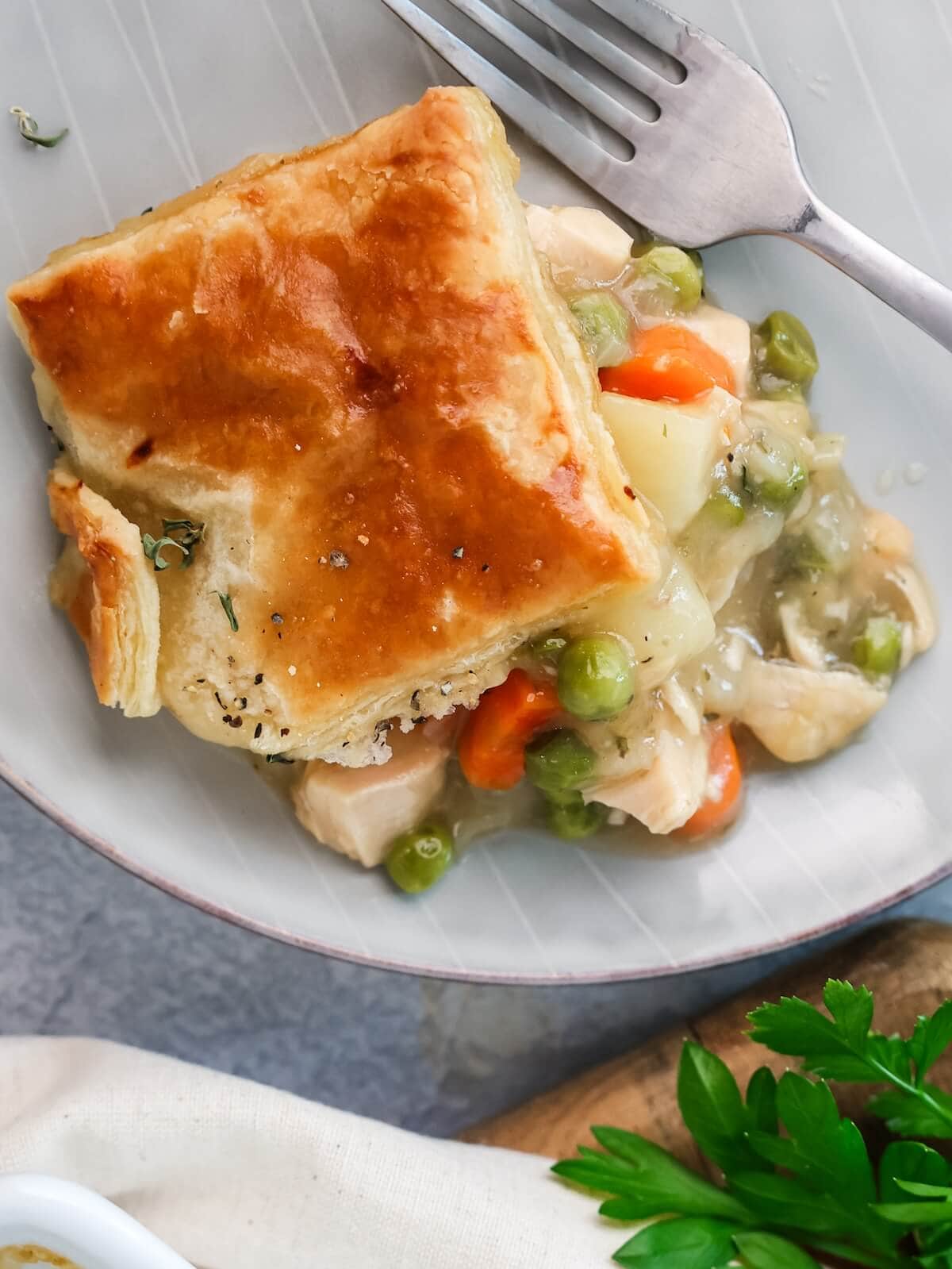 Serving of turkey pot pie with puff pastry crust on a plate.