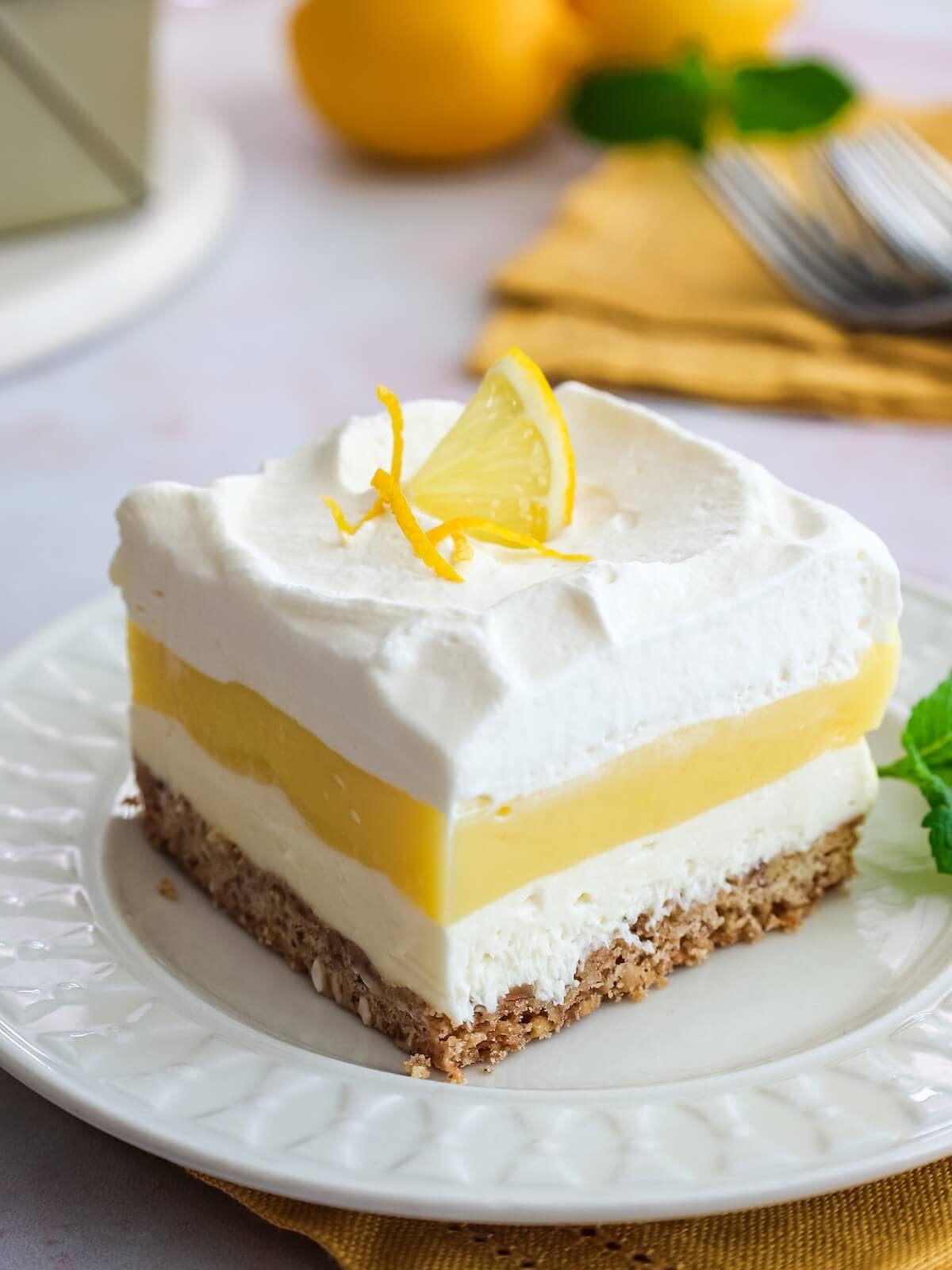 Beauty slice of lemon lush with layers of cream cheese, lemon curd, and whipped cream.