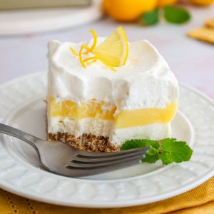 Feature image of layered lemon lush dessert with a bite out.