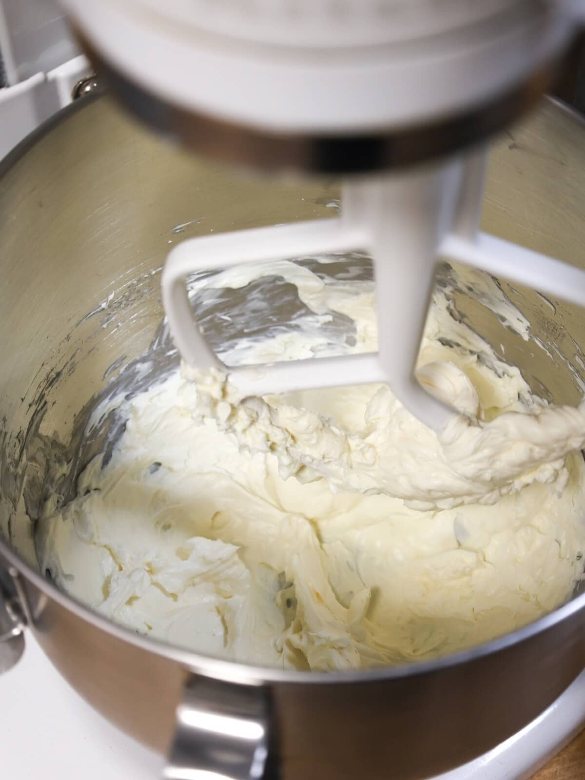 Mixing cream cheese until smooth before adding butter for cream cheese frosting.