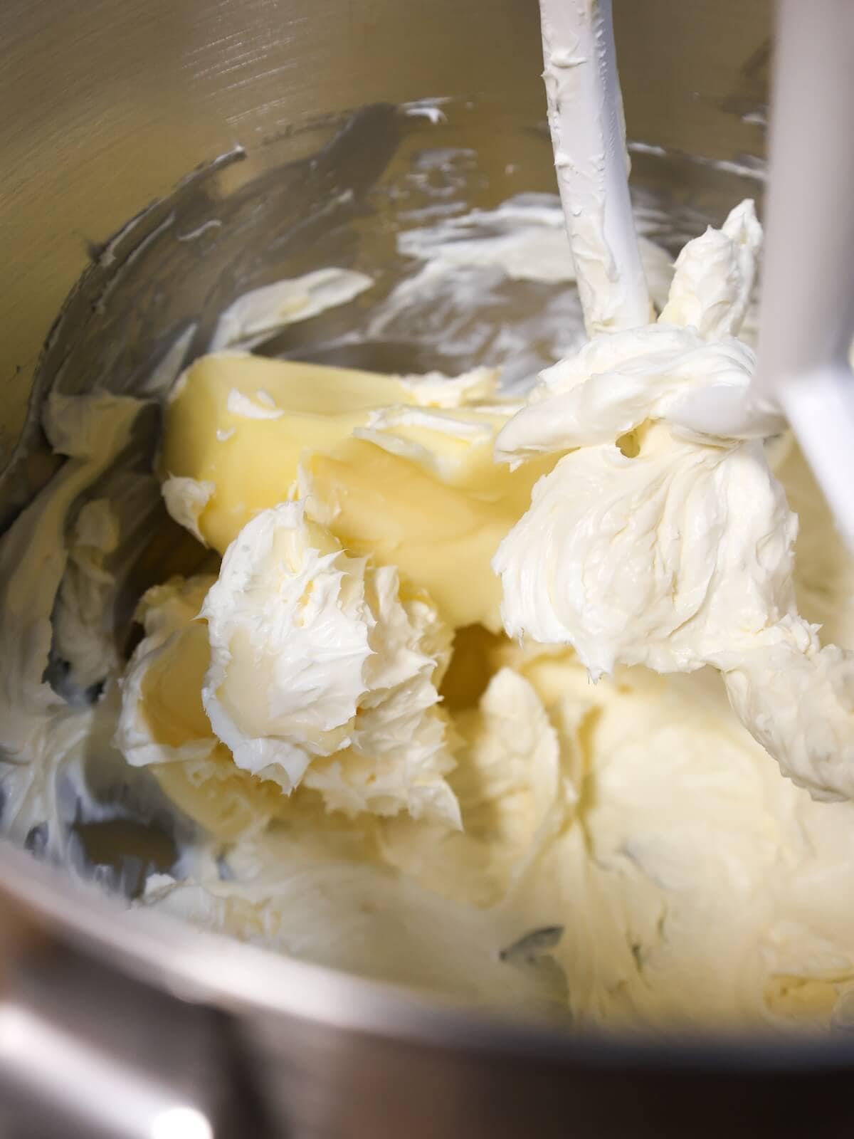 Adding soft butter to cream cheese frosting.