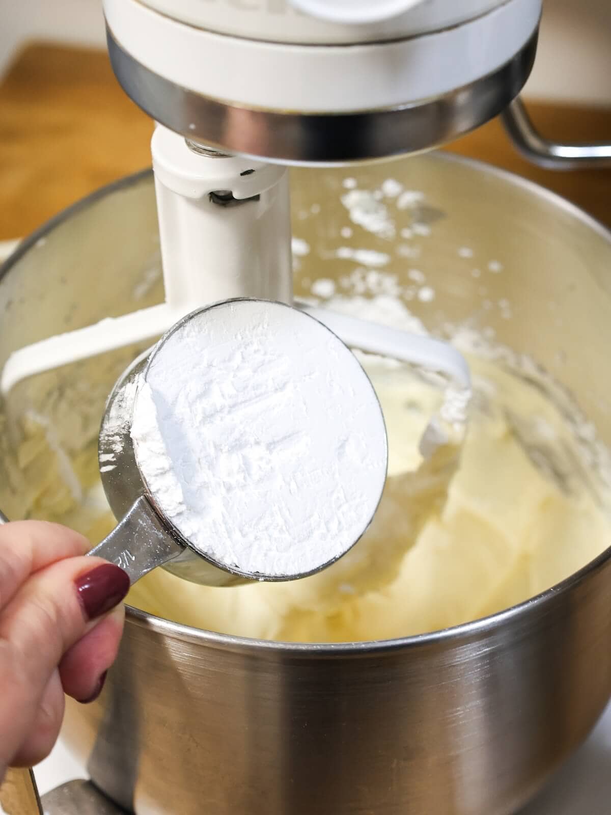 Adding confectioners' sugar a little at a time to frosting.