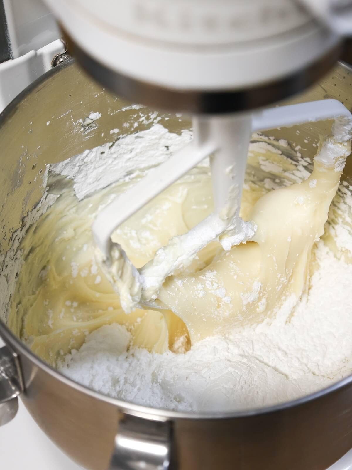 Mixing cream cheese frosting until smooth.