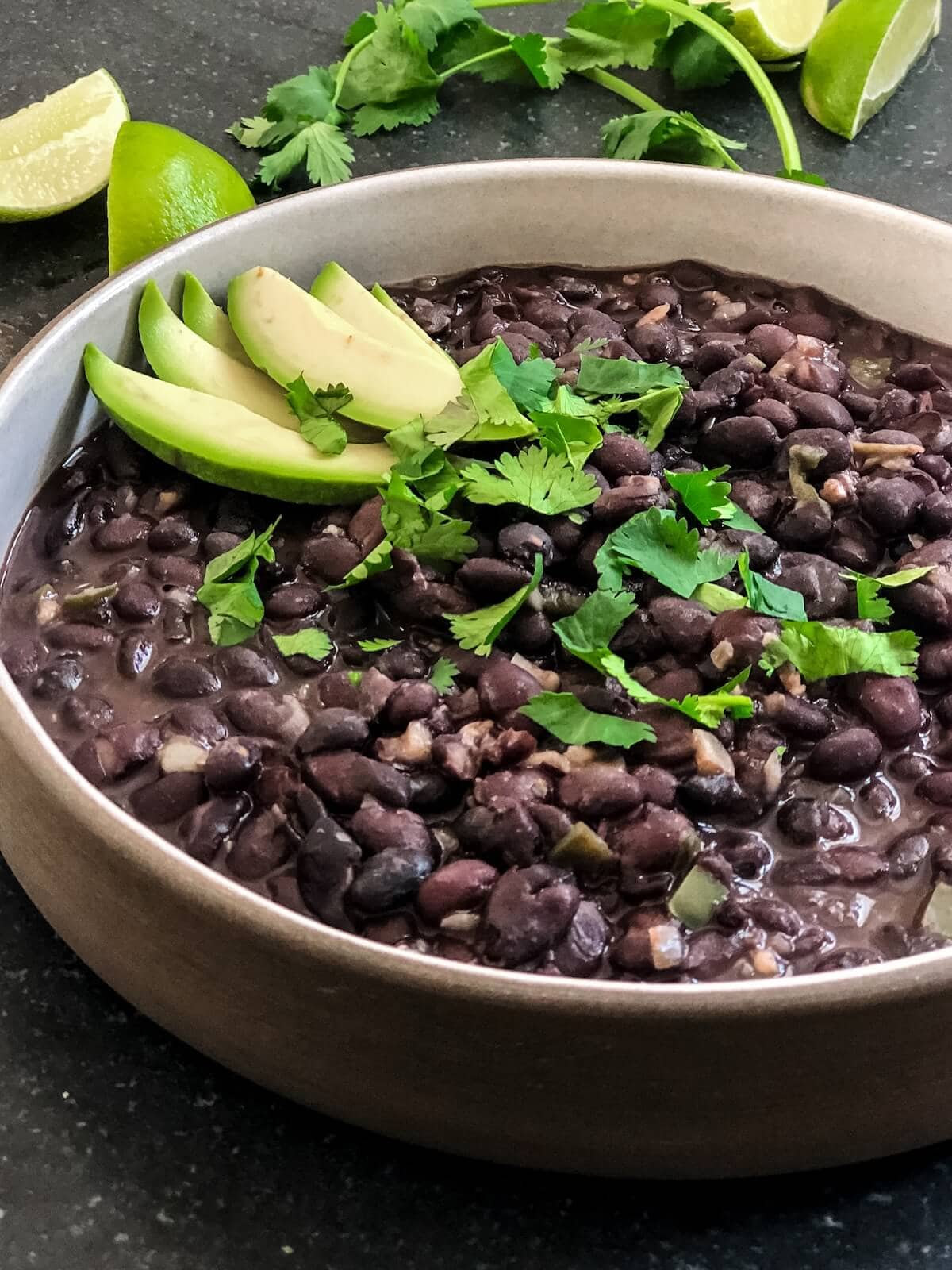 close up of creamy black beans in a bowl with avocado