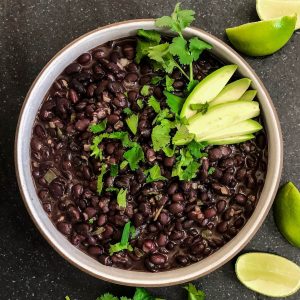 square feature overhead looking into a bowl of black beans with onions and jalapenos in creamy sauce.