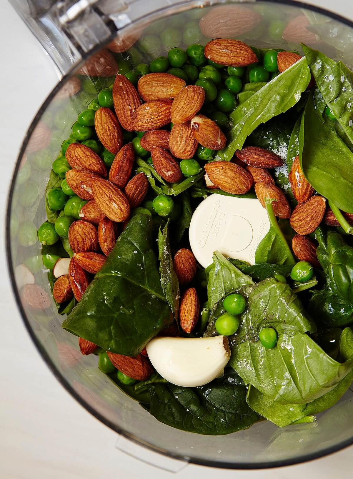 making pesto with almonds, basil, garlic, and spinach with peas.