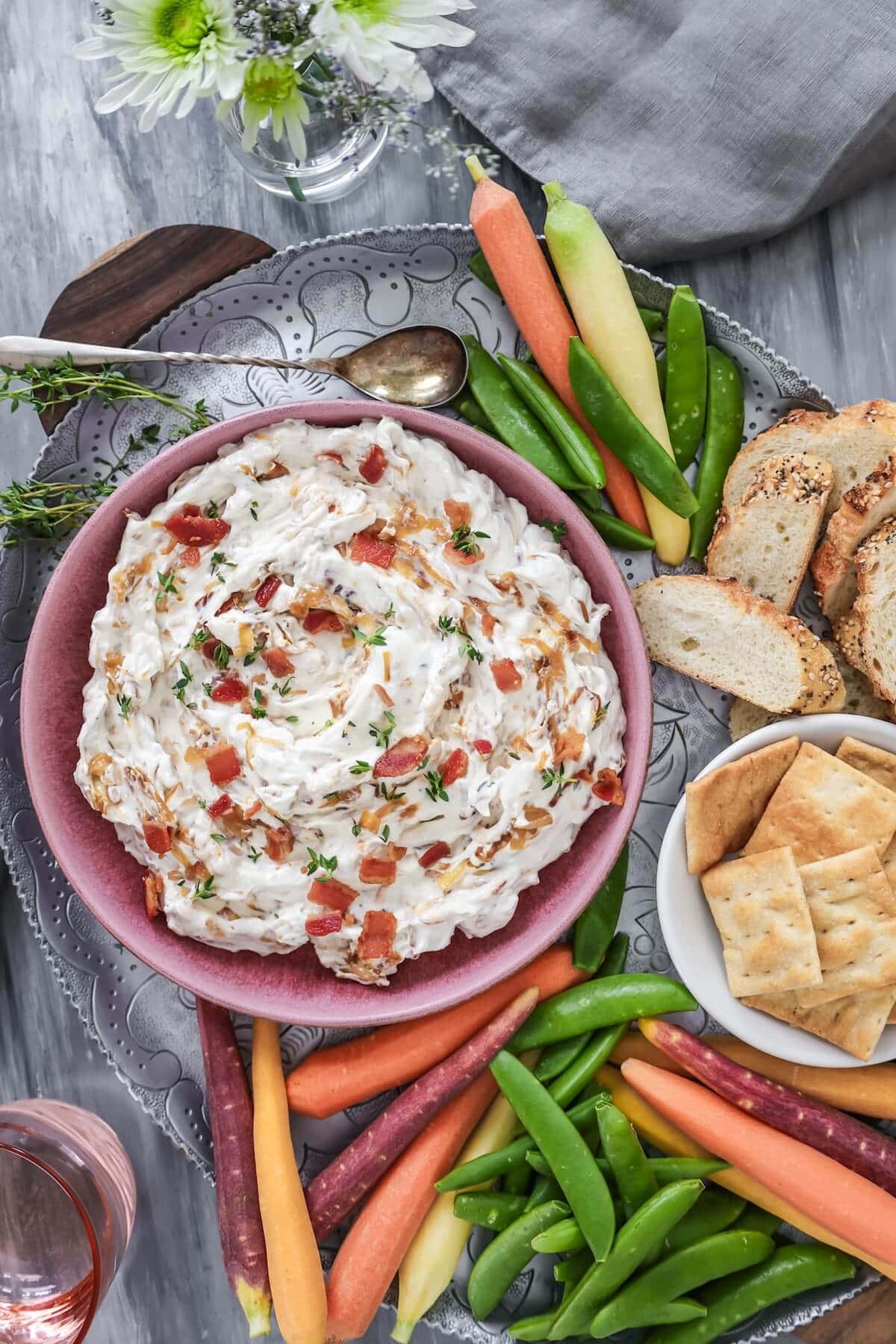 onion bacon dip on party table with veggies and dippers.