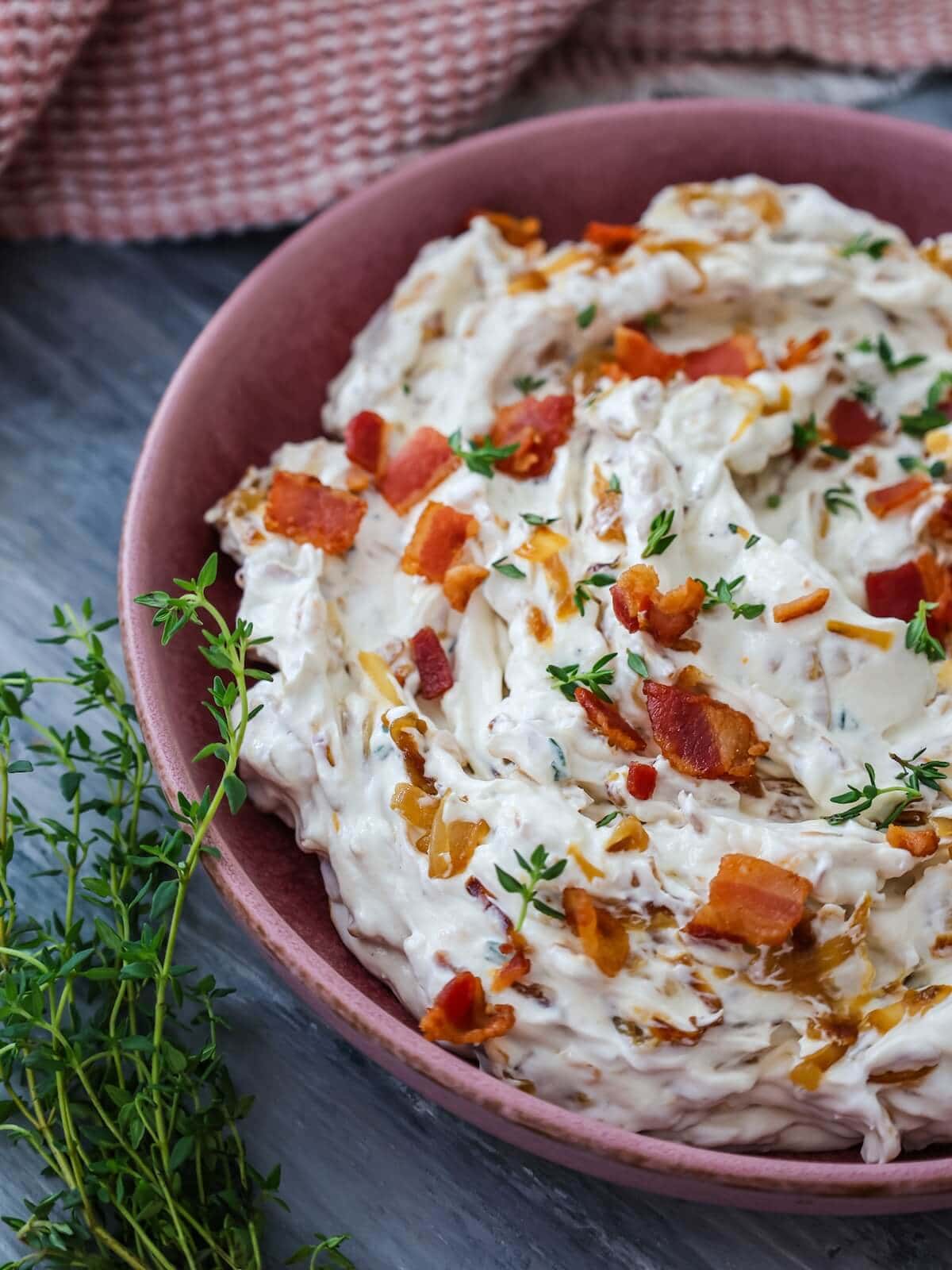 close up of caramelized onion bacon dip with thyme garnish.