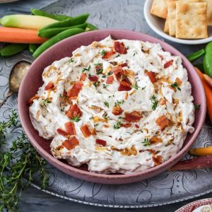 close up feature of caramelized onion dip in pink bowl.