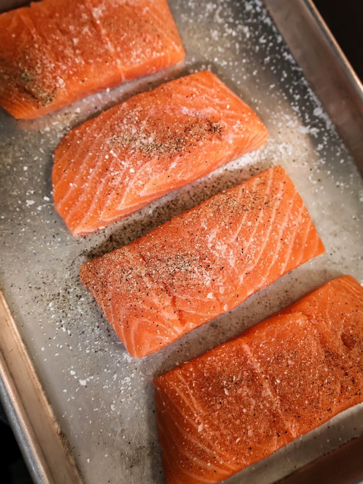 seasoning salmon before cooking.