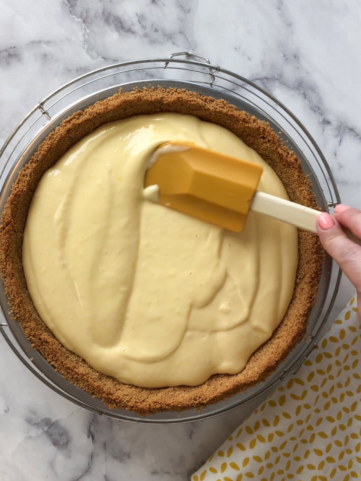 Spreading mango filling evenly into the crust using a spatula.